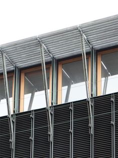 an airplane is flying in the sky over a building that has many windows and metal bars on it