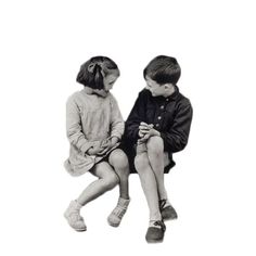 two young children sitting next to each other on a white background, looking at something