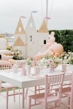 a table set up with pink chairs and balloons