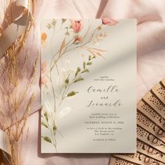 a wedding card with flowers on it next to some fan and other items that are laying around