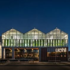 a building that has some glass on the front and side of it at night time