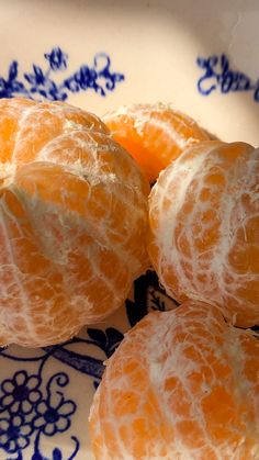 four peeled oranges sitting on top of a blue and white plate