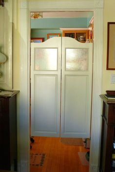 an open door leading into a kitchen with wooden floors and cabinets on either side of the room