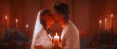 a bride and groom kissing in front of candles