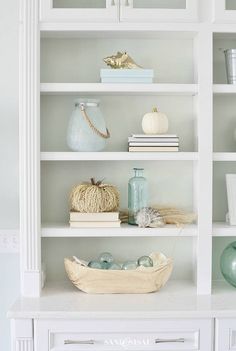 a white bookcase filled with books and vases