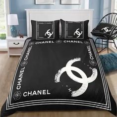 a black and white bed set with chanel logo on it in a blue room