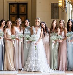 a group of women standing next to each other wearing dresses and holding bouquets in their hands