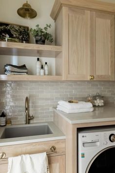 a washer and dryer in a small room with wooden shelves above the sink