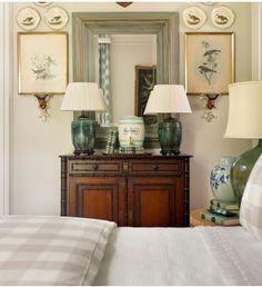 a bed room with a neatly made bed and two lamps on top of the dresser