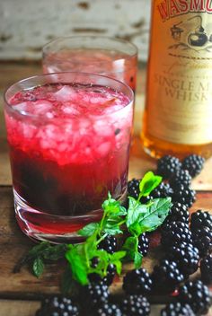 a glass filled with liquid next to some blackberries