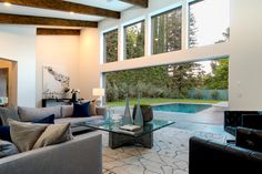 Luxury indoor outdoor living room design in chic modern Beverly Hills home has a sliding glass wall that opens up the room to the pool & terrace. Indoor Outdoor Living Room, Modern Luxury Living Room, Luxury Living Room Design