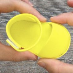 two hands holding yellow cups on top of a wooden table