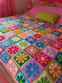 a bed covered in colorful crocheted bedspread next to a pink wall