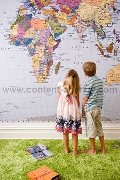 two children standing in front of a wall map