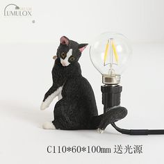 a black and white cat figurine sitting next to a light bulb