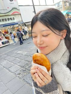 a woman is eating a donut on the street