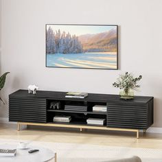 a living room with a painting on the wall and a black entertainment center in front of it