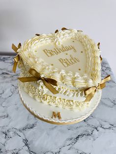 a heart shaped birthday cake sitting on top of a marble counter next to a white wall