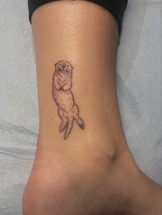 a small tattoo on the ankle of a woman's foot that has an otter in it