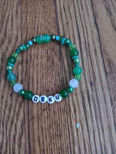 a green beaded bracelet with the word dek written in white letters on it