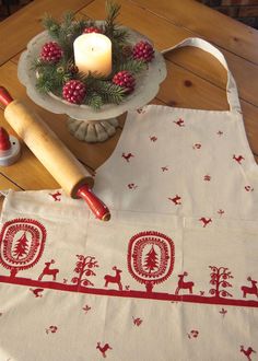 a table with an apron and candle on it, next to a christmas tree decoration