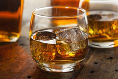 three glasses filled with alcohol on top of a wooden table