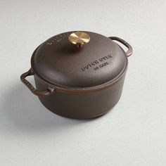 a brown pot with a gold lid on a white surface