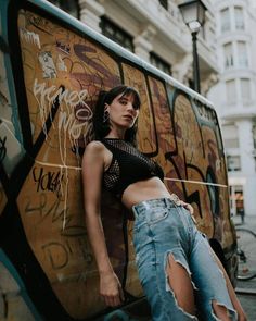 a woman leaning against the side of a van with graffiti all over it's walls