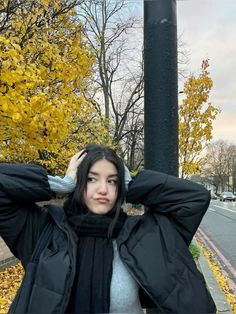 a woman standing next to a pole with her hands on her head and looking at the camera