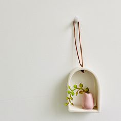 a ceramic vase hanging on the wall with a string attached to it's side