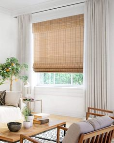 a living room filled with furniture and a window covered in white draping next to a wooden coffee table