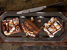 three pieces of cake on a metal tray with a knife and fork next to it