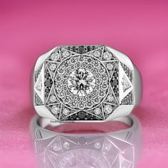 a white gold ring with black and white diamonds in the center on a pink background