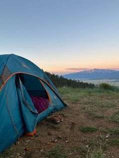 a blue tent sitting on top of a grass covered field