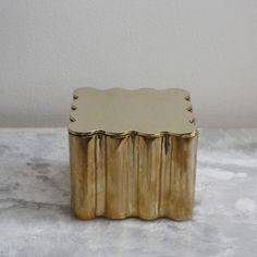 a small gold box sitting on top of a marble counter next to a white wall