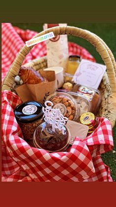 a picnic basket filled with food on top of a red and white checkered blanket