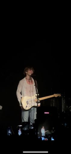 a man standing next to a guitar on top of a stage