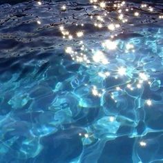 the water is very clear and blue with little lights on it's surface in the pool