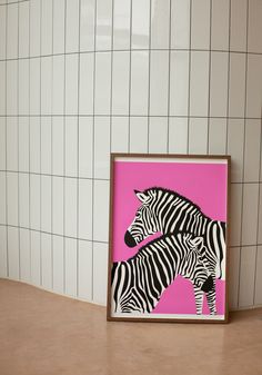 two zebras standing next to each other in front of a pink and white tile wall