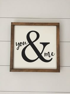 a sign that says you and me hanging on the side of a white wooden wall