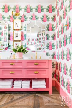 a bathroom with pink vanity and wallpaper on the walls, decorated with pineapples