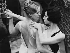 black and white photograph of two women in evening dresses, one holding the other's back