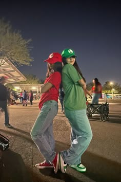 two skateboarders in green and red shirts are standing on the street with their arms around each other