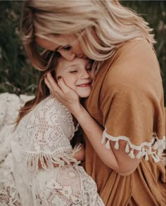 a woman is hugging her child on the ground