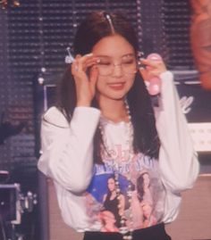 a young woman wearing glasses and holding her hands up to her face while standing in front of a microphone