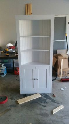 a white bookcase sitting in the middle of a room with tools on the floor