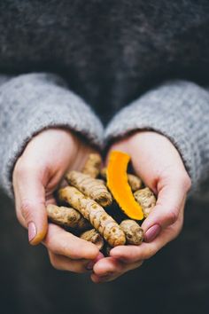 two hands holding small pieces of food in the palm of someone's hands, with an orange peel sticking out of it