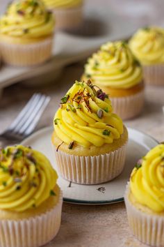 several cupcakes with yellow frosting and sprinkles on a plate