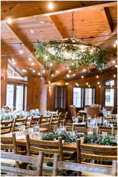 the tables are set with place settings and greenery hanging from the ceiling above them