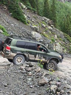 a green truck driving down a rocky road